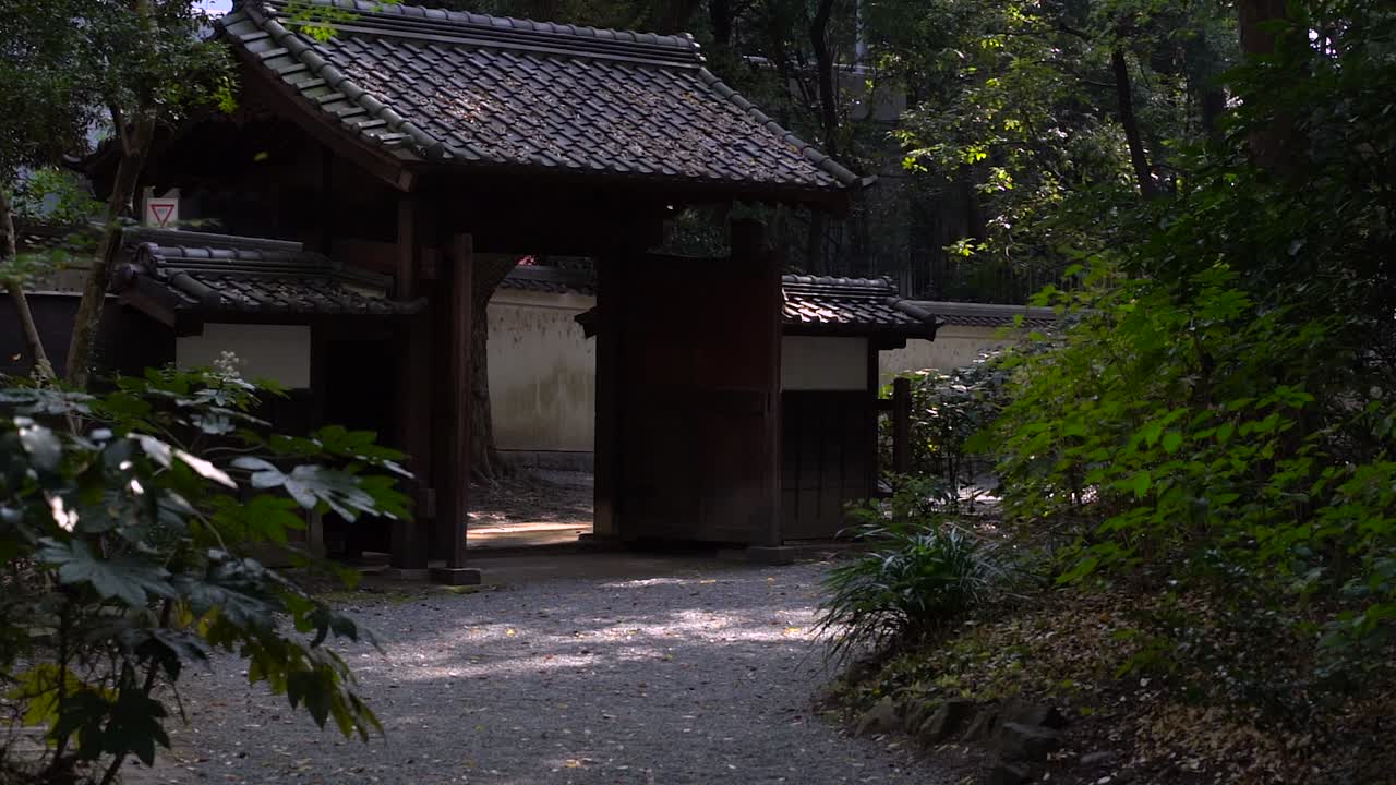 慢慢地向木製的日本大門進去 在美麗的綠色中