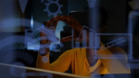 blue digital icons floating against african american businesswoman wearing vr headset at home