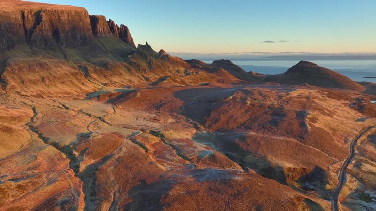 Uneven winter moorland bathed in dawn light with flight towards Quiraing cliffs
