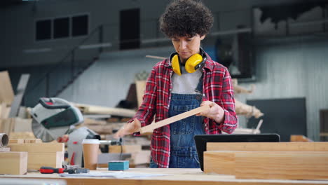 woman woodworker inspecting wood plank in workshop
