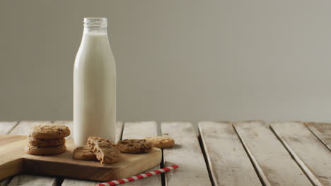 video of glass bottles of milk and cookies on wooden table on white background