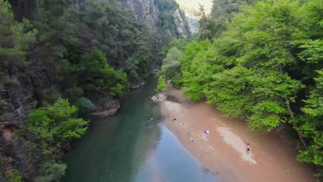 Drohne-Steigt-Ab-Und-Fliegt-Durch-Den-Fluss-Zwischen-Hohen-Canyon-Klippen