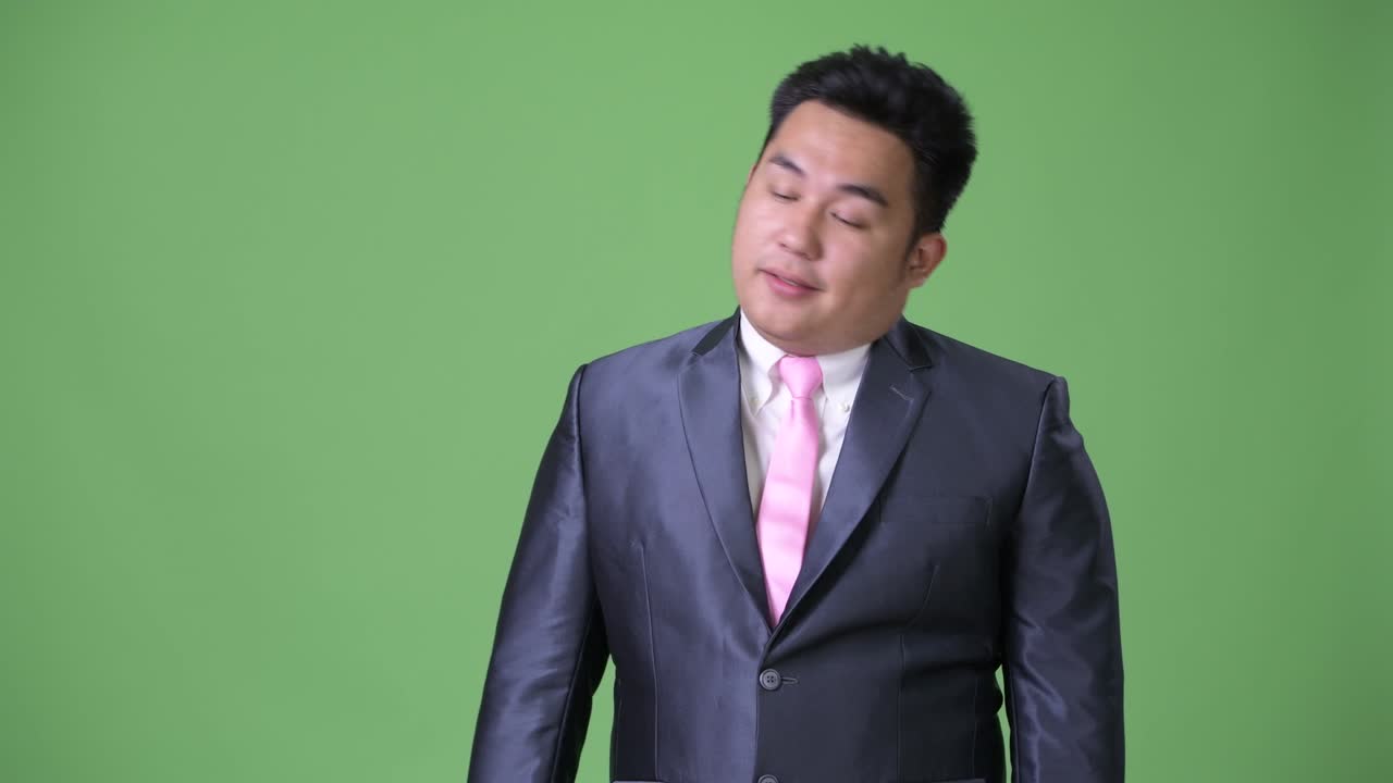 초록색 배경에 젊은 잘생긴 과체중 아시아 사업가