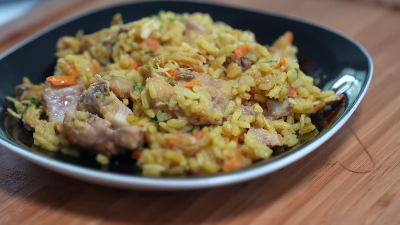 Vibrant Colombian Arroz Con Pollo on a sleek black plate, showcasing tender chicken, rice, and vegetables in warm lighting, offering a mouthwatering view of traditional cuisine