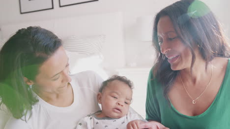 millennial mother sitting holding her baby son,her mother beside them, close up, lens flare