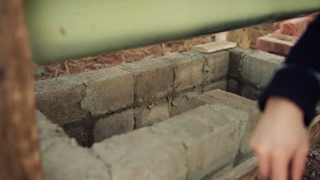 the man is blending the cement before applying it to the concrete blocks beneath the diy hot tub - close up