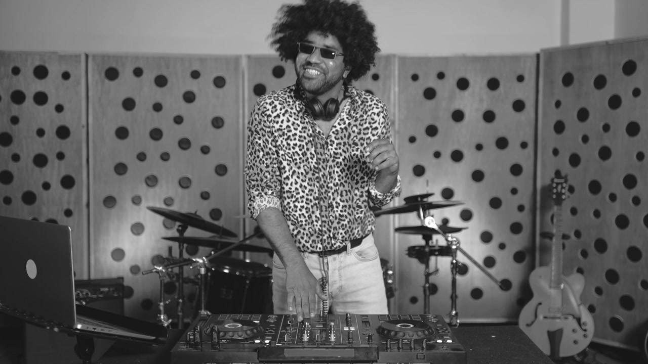 Uomo energico che fa il DJ e balla in uno studio musicale in bianco e nero