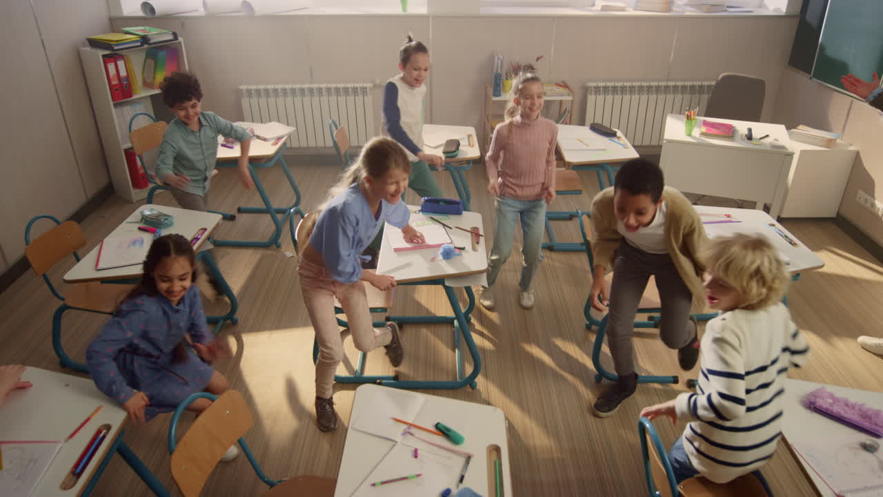 Children sitting at school desks. Students running from classroom for break