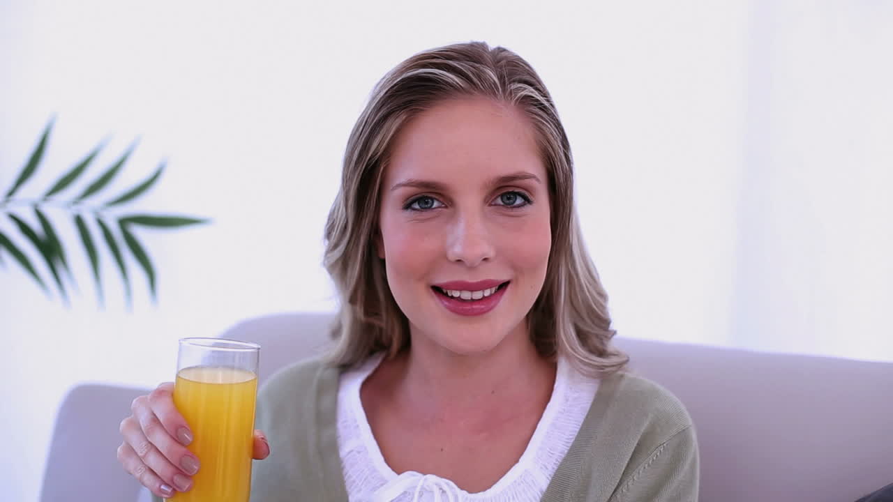 hermosa mujer rubia bebiendo un vaso de jugo de naranja
