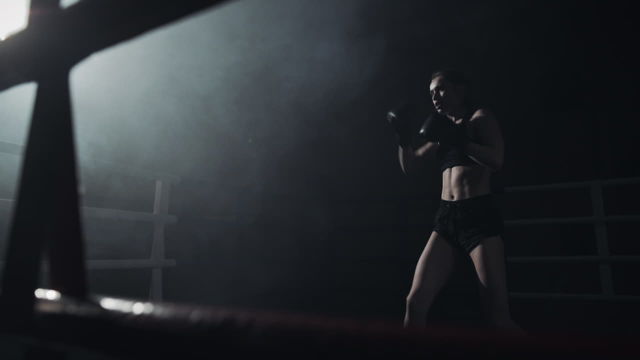 Female Boxer Training in a Dimly Lit Ring