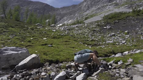 hiker drinking water from mountain stream, rockies, kananaskis, alberta canada