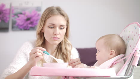 Mamá-Alimenta-Al-Niño-En-Una-Silla-De-Bebé.-Mujer-Alimentando-Al-Bebé-Con-Gachas