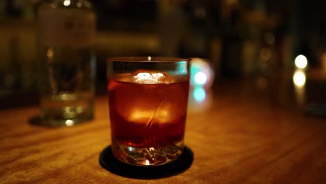 hand taking a cocktail from a dimly lit bar