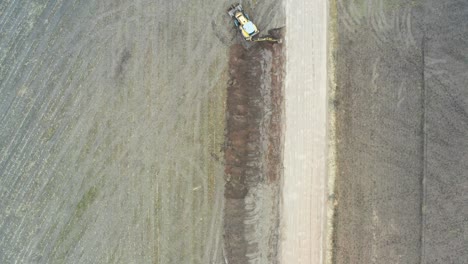 vista aérea de gran altitud de excavación y reparación de drenaje de tractor cerca de la carretera