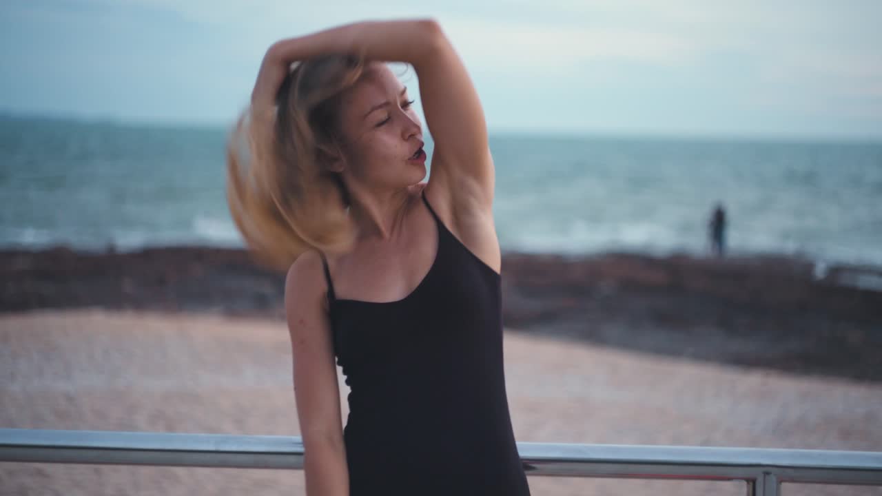 Portret van een blonde Kaukasische vrouw op een strand die haar haar aanraakt op een winderige dag