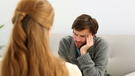 young man sitting on sofa talking to his therapist