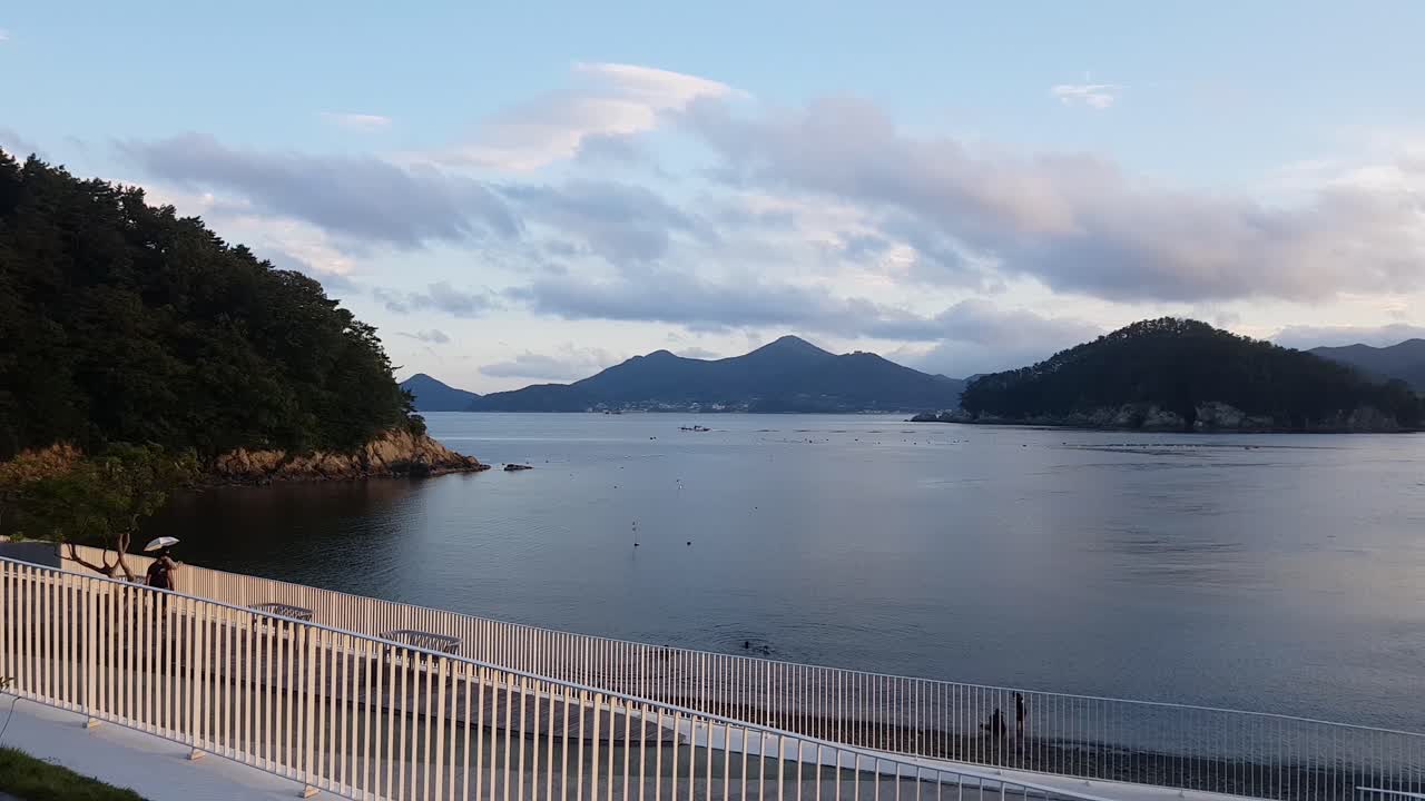 한국 한화 리조트 벨베데레의 잔잔한 바다에서 수영하는 사람들을 지켜보는 관광객 한 쌍