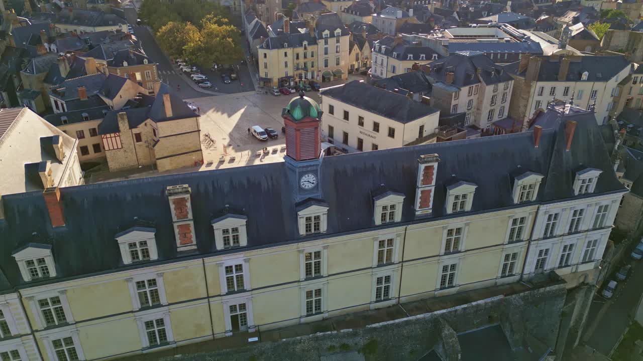Drone moves forward toward the clock tower and green dome of Château Neuf in Laval, with surrounding buildings under sunlight