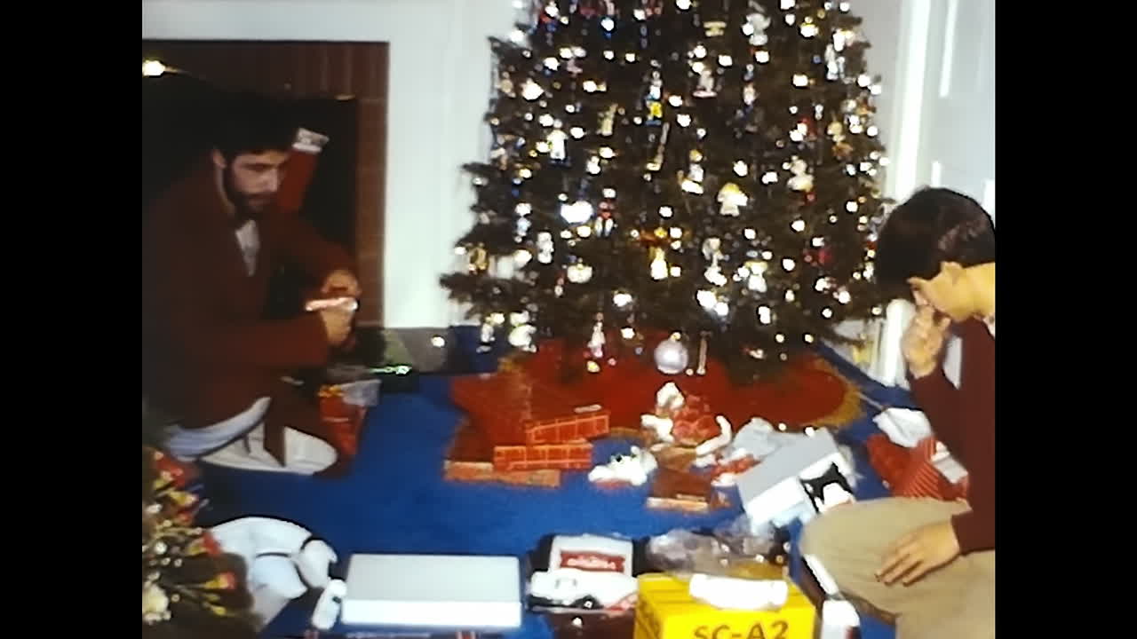 Man Sitting in Front of Christmas Tree. CIRCA USA - 1970s: A man from the 1970s sits in front of a Christmas tree in this historic video archive from the USA.