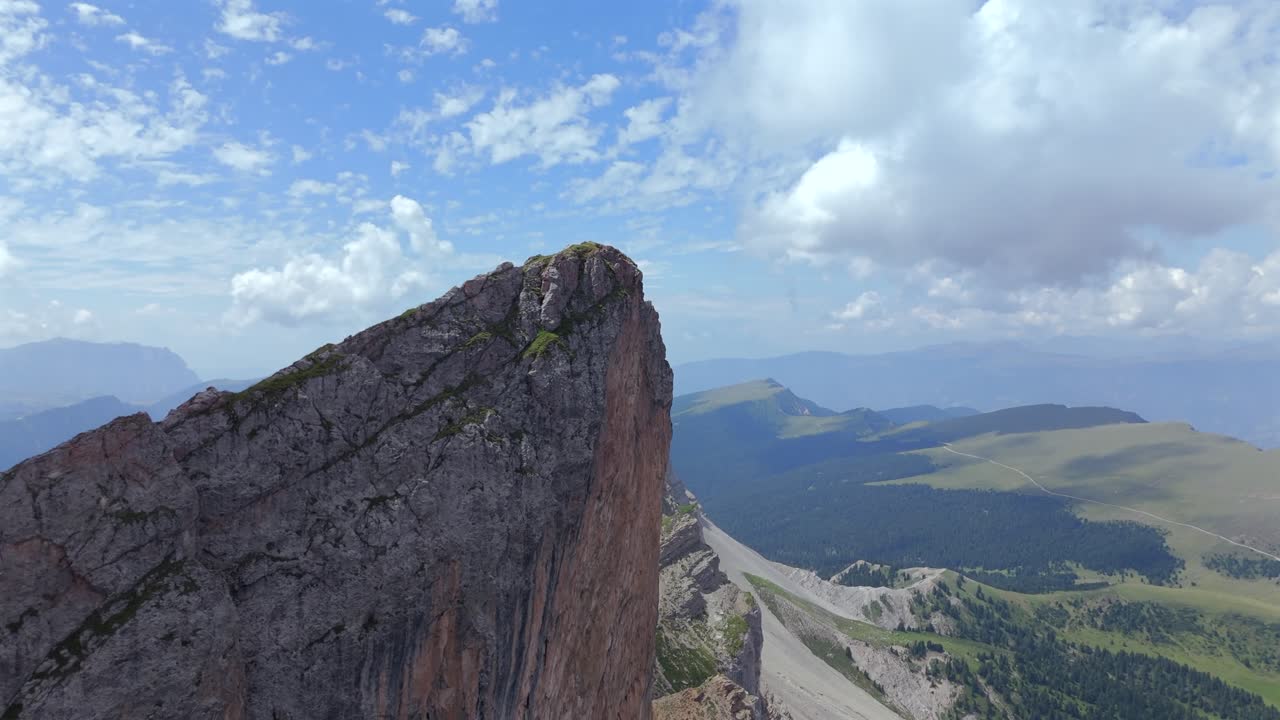 dramático primer plano aéreo de un pico escarpado y rocoso en los dolomitas, italia, con vistas panorámicas de verdes valles y montañas lejanas
