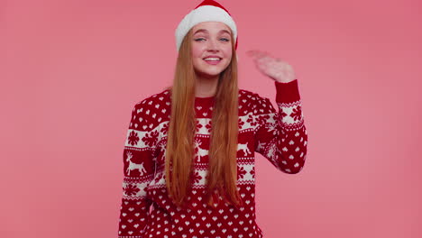 woman in christmas sweater waves hand palm in hello gesture welcomes someone to celebrate new year