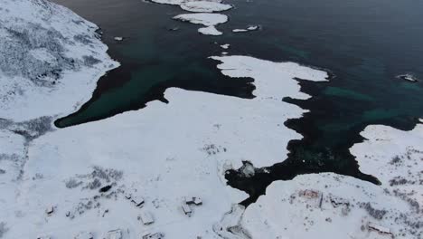 Drohnenansicht-In-Der-Gegend-Von-Tromsø-Im-Winter,-Die-über-Eine-Verschneite-Landschaft-Fliegt,-Umgeben-Von-Klarem,-Blauem-Wasser-Und-Holzhäusern-In-Norwegen