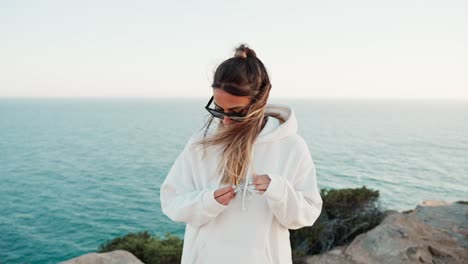 Slow-motion-shot-of-an-attractive-woman-standing-playing-with-her-hair-at-the-coast