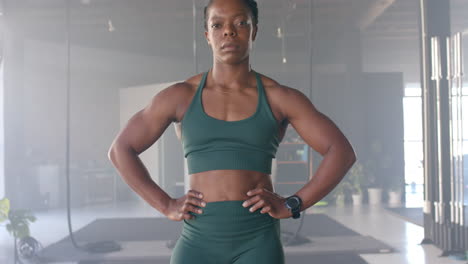 confident woman in gym wearing fitness attire, standing with hands on hips
