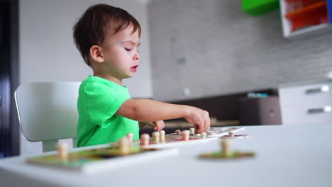 lovely toddler is concentrated on his game. little baby boy fitting puzzle. blurred backdrop.
