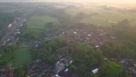 Aerial-drone-shot-approaching-silhouette-of-Telecommunication-Tower-during-foggy-mystic-day-and-sunset---Supplying-small-rural-villages-with-network-and-electricity