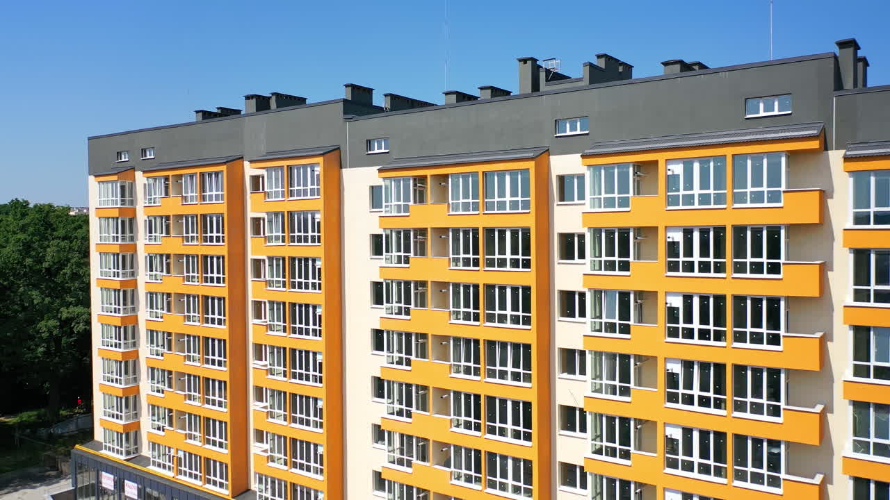 Facade of a new house for city residents. Modern apartment building with large windows and colorful walls in sunny summer day.