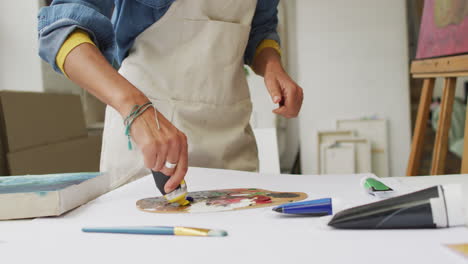 artist mixes paint on a palette in a bright studio, with copy space