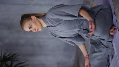 elegant woman in stylish blue robe sitting in lotus pose