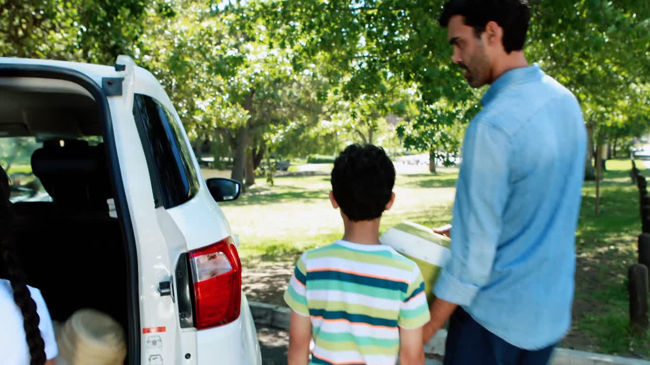 familia en un picnic quitando la canasta del coche