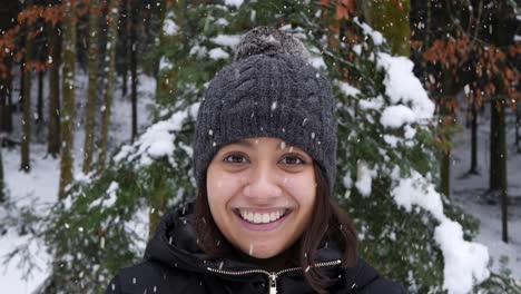 beautiful asian woman looking towards camera and smiles in forestry area during snowfall