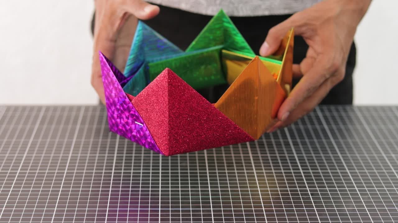 mani che mostrano una corona color arcobaleno fatta di materiale pvc in colori metallici