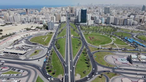 4k:-Vista-Aérea-Del-Horizonte-De-La-Ciudad-De-Sharjah,-Tráfico-De-La-Ciudad-En-El-Puente-De-Sharjah-Durante-Un-Día-Soleado,-Emiratos-árabes-Unidos