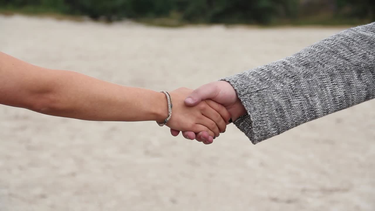mano masculina extendiéndose y siendo tomada por la mano de una mujer joven