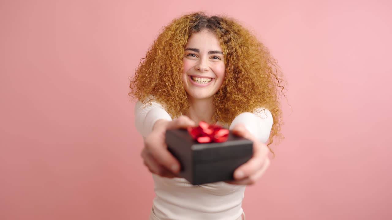 Happy woman giving a gift on pink background