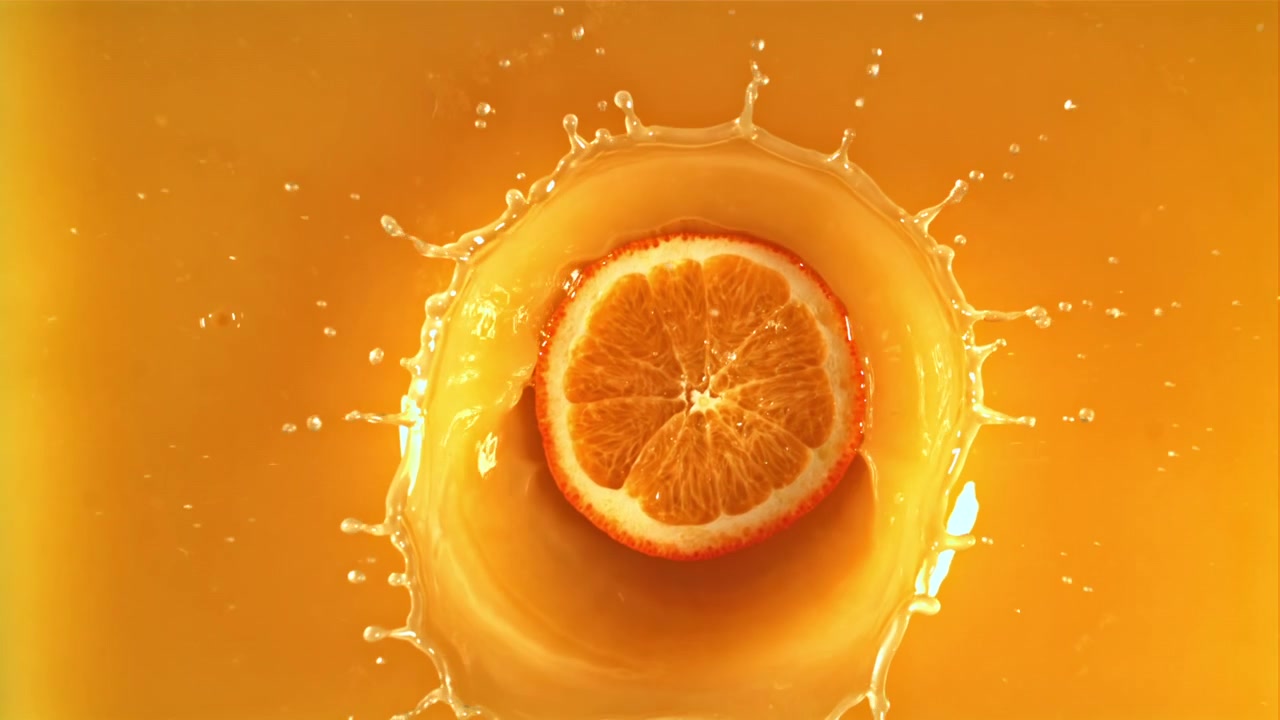 Orangenscheibe spritzt in Zeitlupe in frischen Orangensaft.
