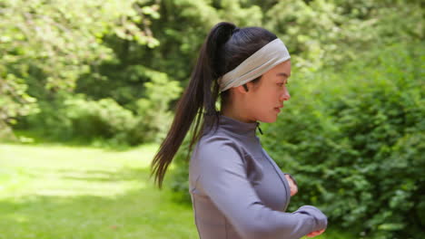 Young-Woman-Stretching-Before-Exercising-Running-Through-City-Park-Wearing-Wireless-Earbuds-3