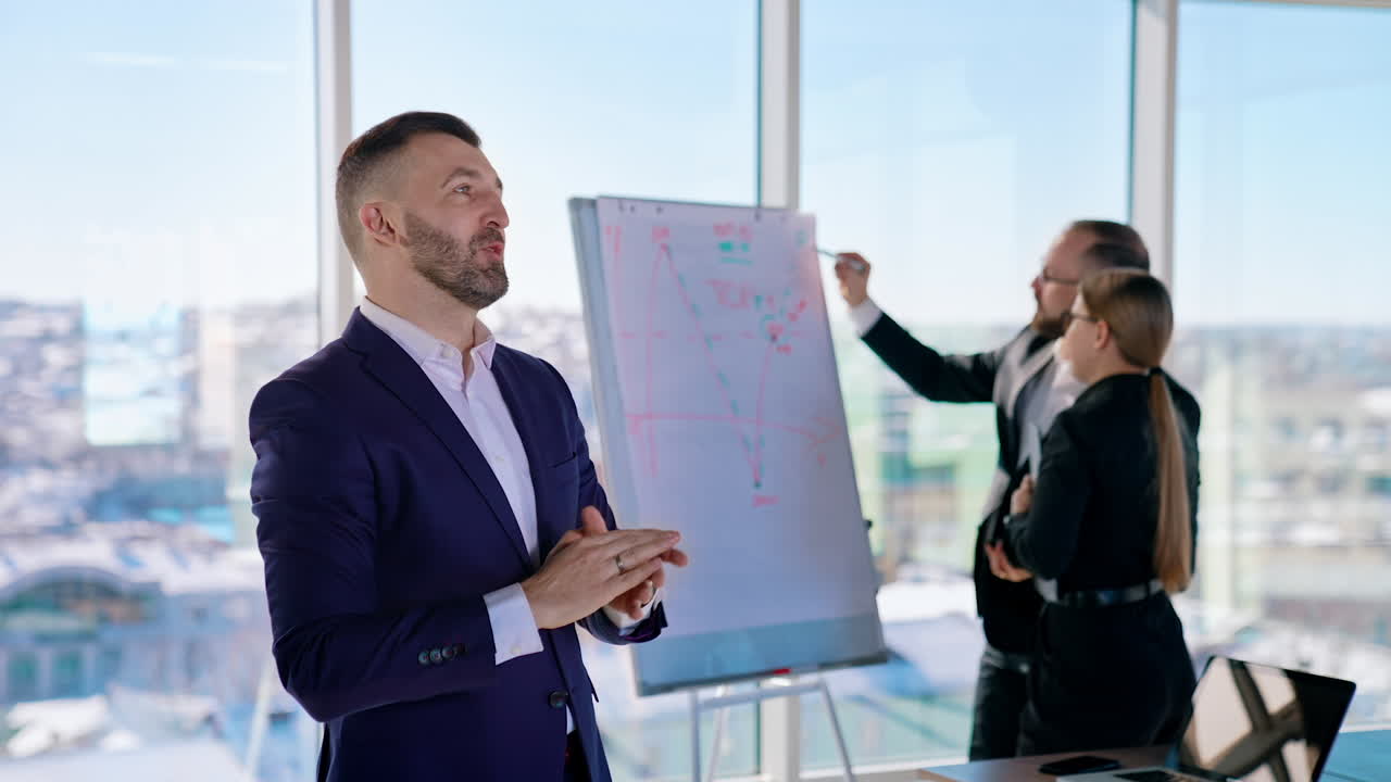 Confident entrepreneur talking about business. Successful businessman explains the achievement of his job on the background of business people in modern office with large windows.