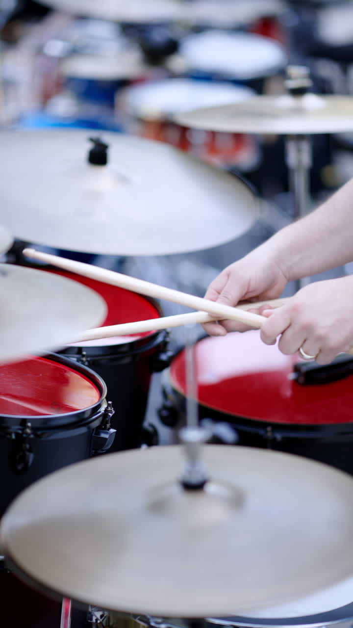 Close up of man playing red drums outside. Vertical