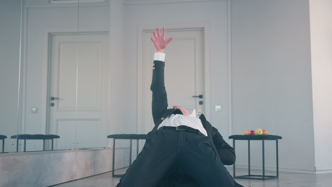young man performs intense dramatic dance with outstretched arm in modern studio, expressive movement highlighted by apples on stool and candle in background