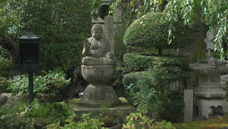 una estatua de buda de piedra está rodeada por un jardín de plantas silvestres