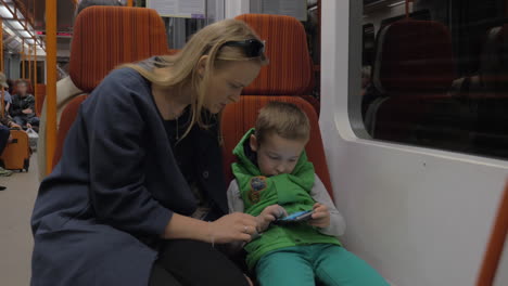 child and mother with mobile phone in subway train