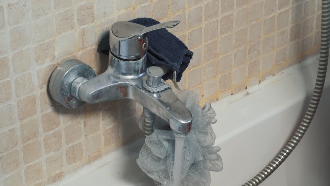 brazo desnudo de mujer cerrando el grifo de la bañera de agua caliente en el baño