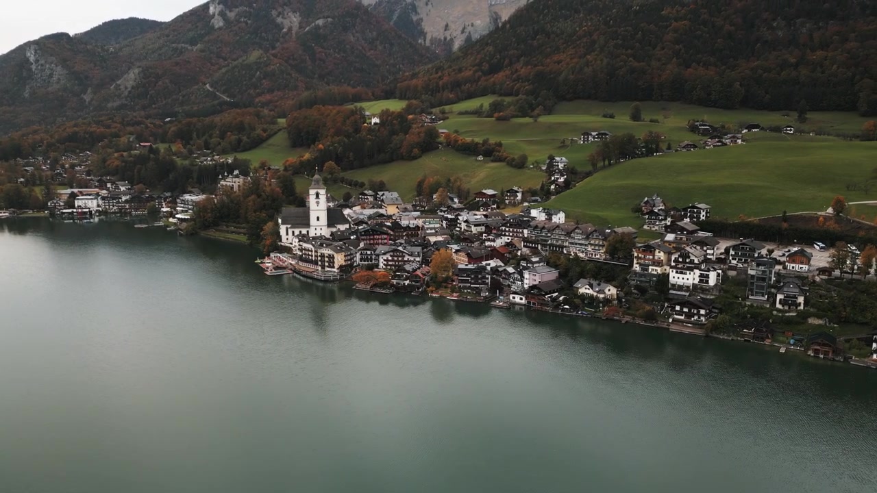 Ripresa aerea in movimento di Wolfgang am Wolfgangsee da lontano in una giornata nuvolosa.