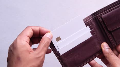 manos abriendo una billetera de cuero marrón con tarjetas de crédito en blanco en el interior.