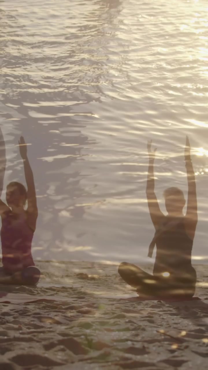Animation of glowing light over senior women practicing yoga by seaside